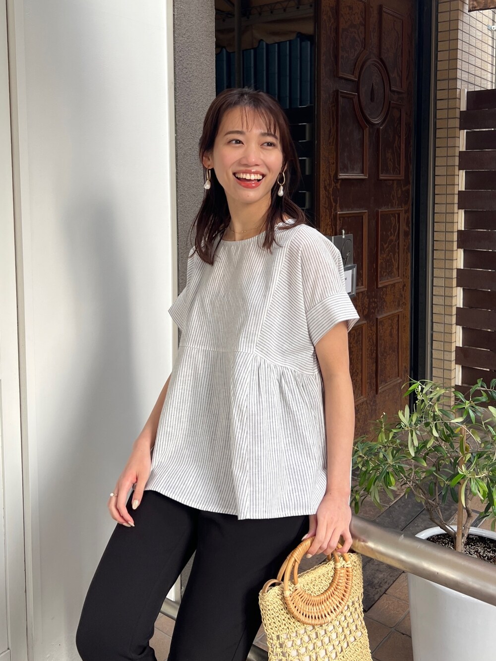 ホワイト系のシャツ/ブラウス、ホワイト系のサンダル、ホワイト系のかごバッグを着用したレディースの春コーディネートの2枚目の写真