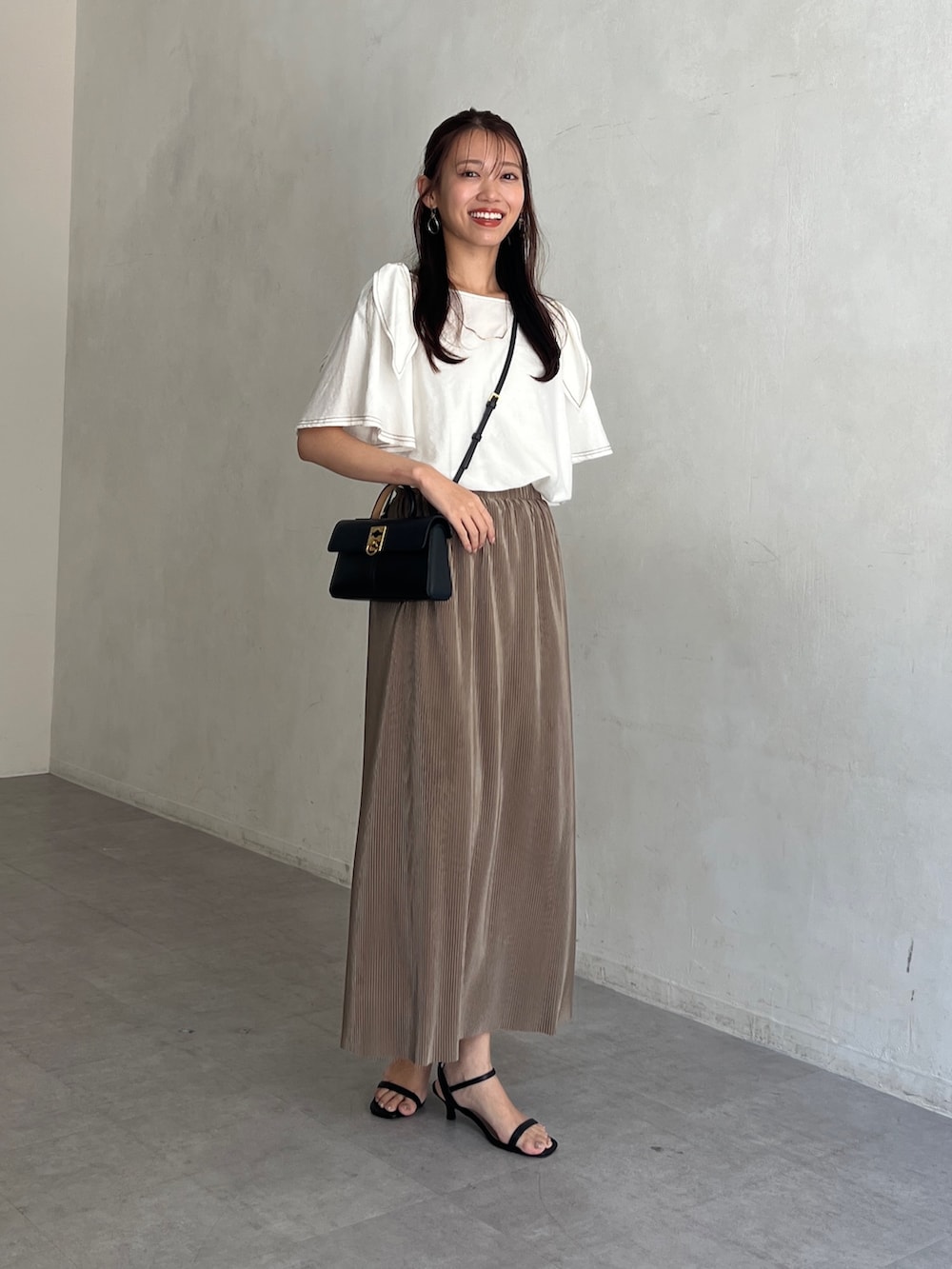 ホワイト系のシャツ/ブラウス、ベージュ系のスカート、ブラック系のサンダルを着用したレディースの夏コーディネートの4枚目の写真