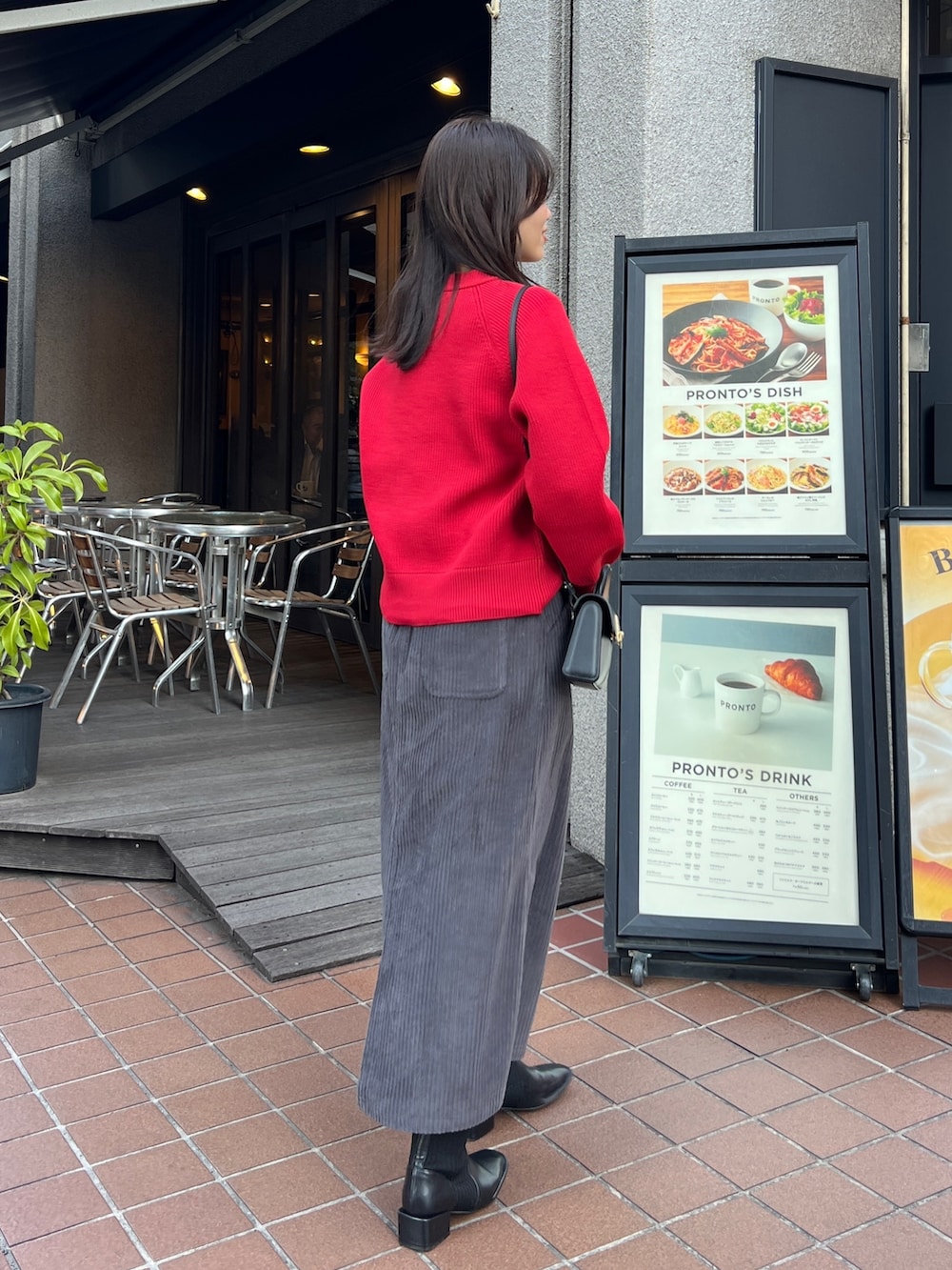 レッド系のニット/セーター、ホワイト系のその他アウター、グレー系のスカートを着用したレディースの冬コーディネートの2枚目の写真