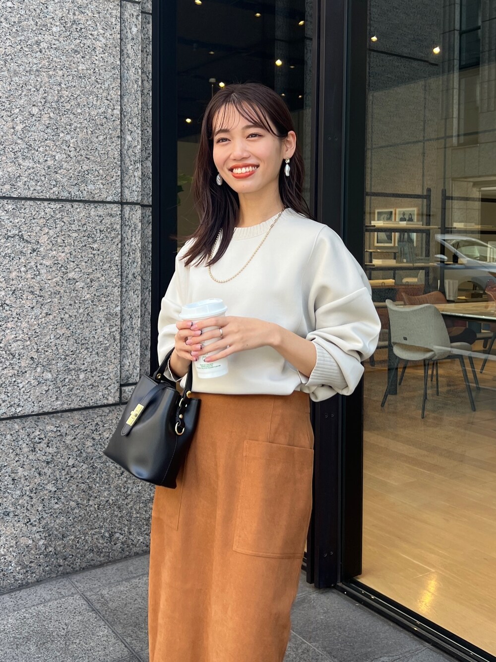 イエロー系のスカート、ブラック系のブーツ、ホワイト系のTシャツ/カットソーを着用したレディースの秋コーディネートの3枚目の写真
