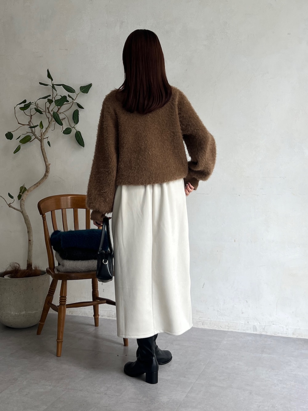 ブラウン系のニット/セーター、ホワイト系のスカート、ブラック系のブーツを着用したレディースの秋コーディネートの2枚目の写真