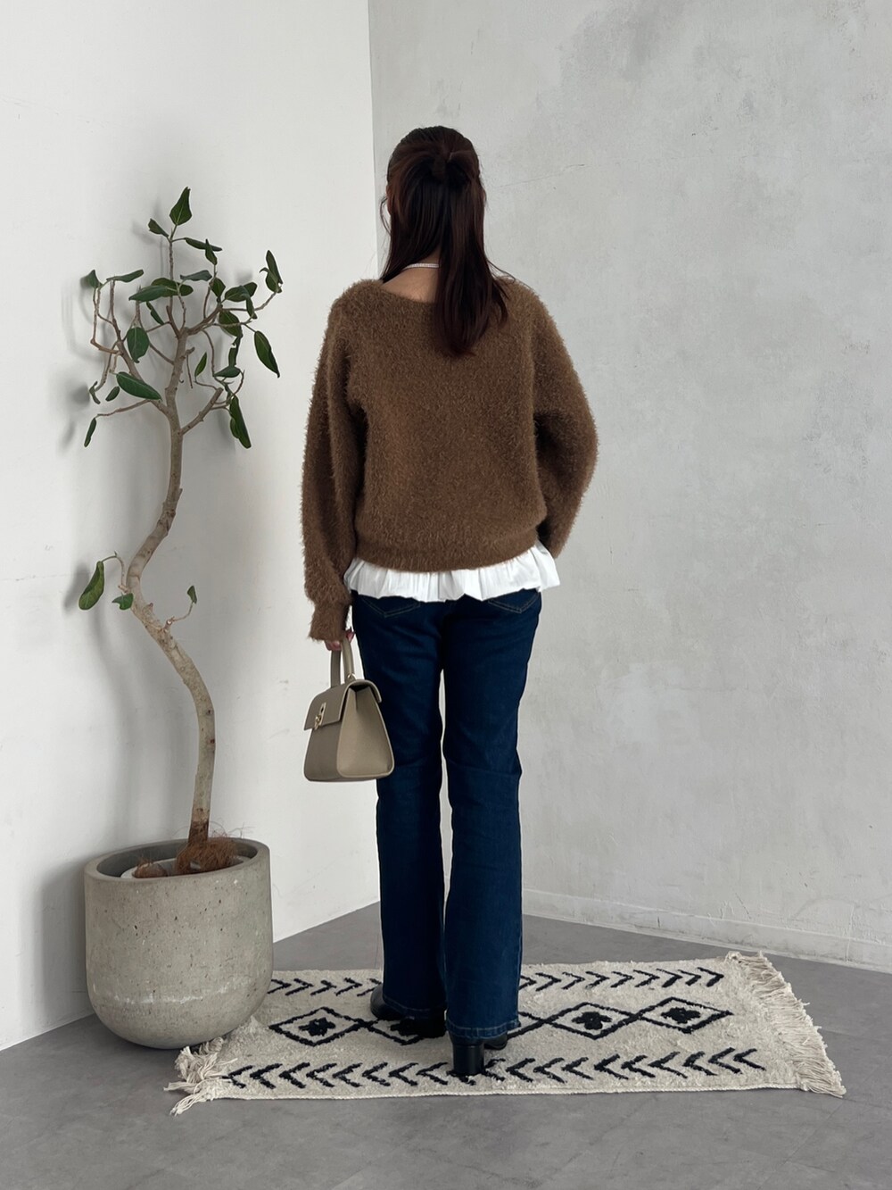 ブラウン系のニット/セーター、グレー系のカーディガン/ボレロ、ブルー系のデニムパンツを着用したレディースの秋コーディネートの3枚目の写真