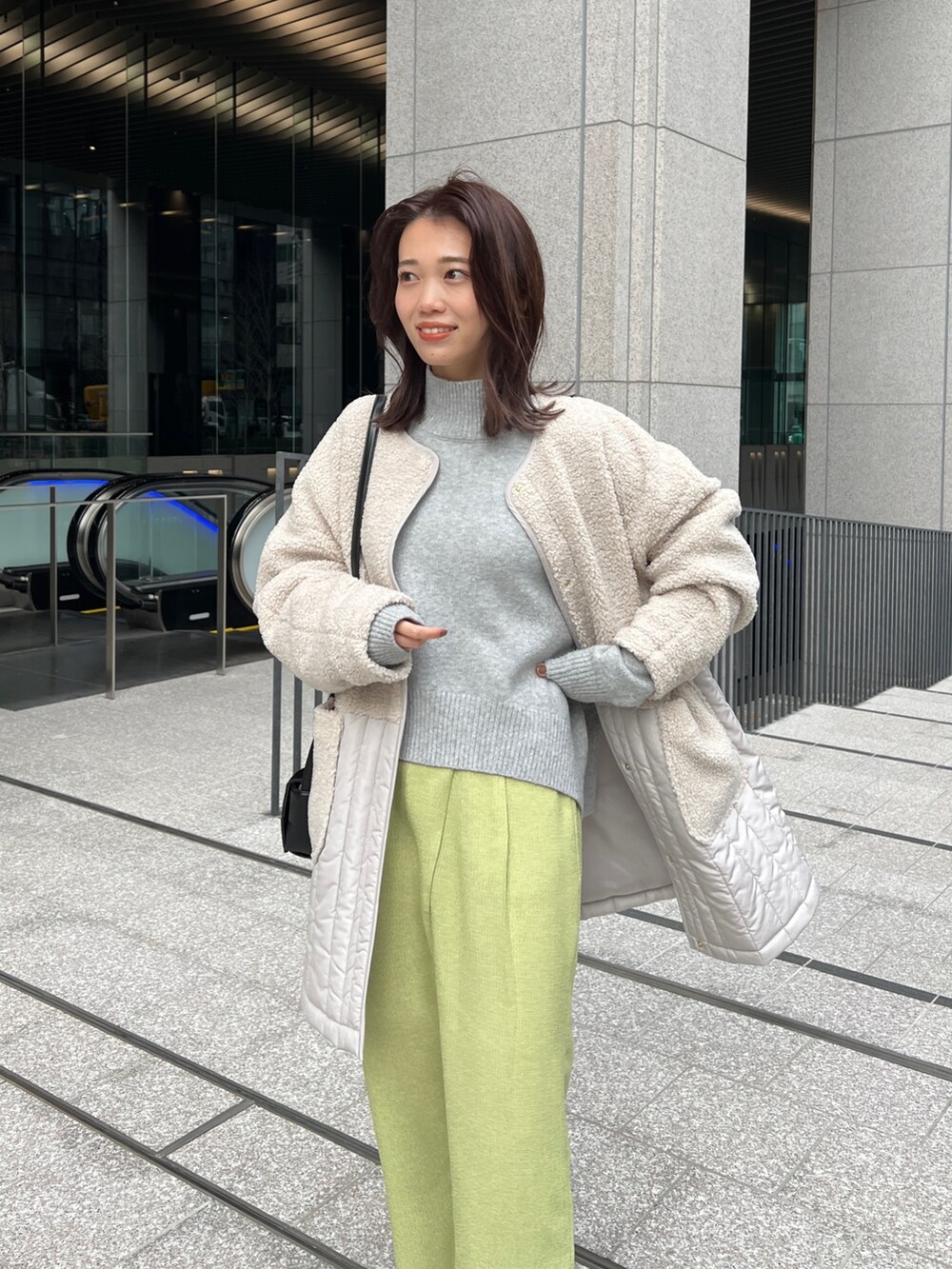 ホワイト系のノーカラージャケット、グレー系のニット/セーター、グリーン系のその他パンツを着用したレディースの冬コーディネートの3枚目の写真