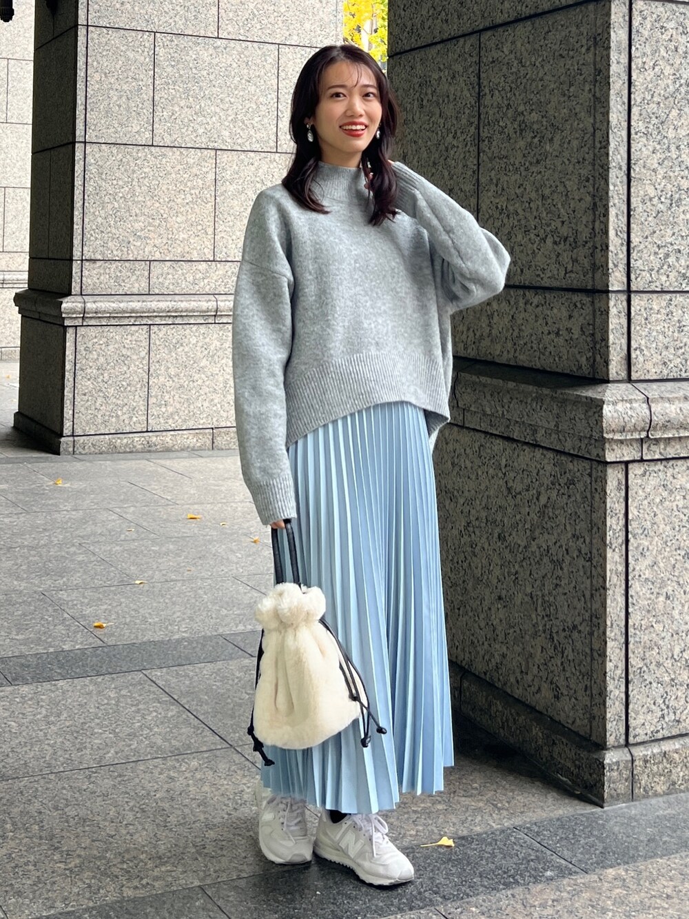 グレー系のニット/セーター、ブルー系のスカート、ホワイト系のトートバッグを着用したレディースの冬コーディネートの2枚目の写真