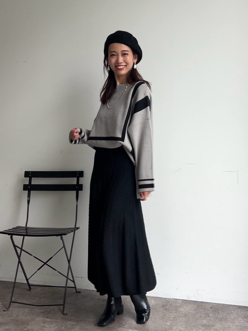 グレー系のニット/セーター、ブラック系のスカート、ブラック系のブーツを着用したレディースの冬コーディネートの3枚目の写真