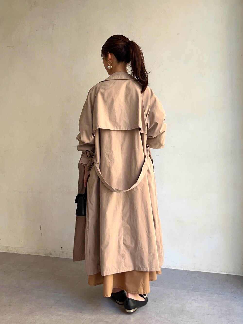 ベージュ系のトレンチコート、イエロー系のワンピース/ドレス、ブラック系のパンプスを着用したレディースの冬コーディネートの2枚目の写真