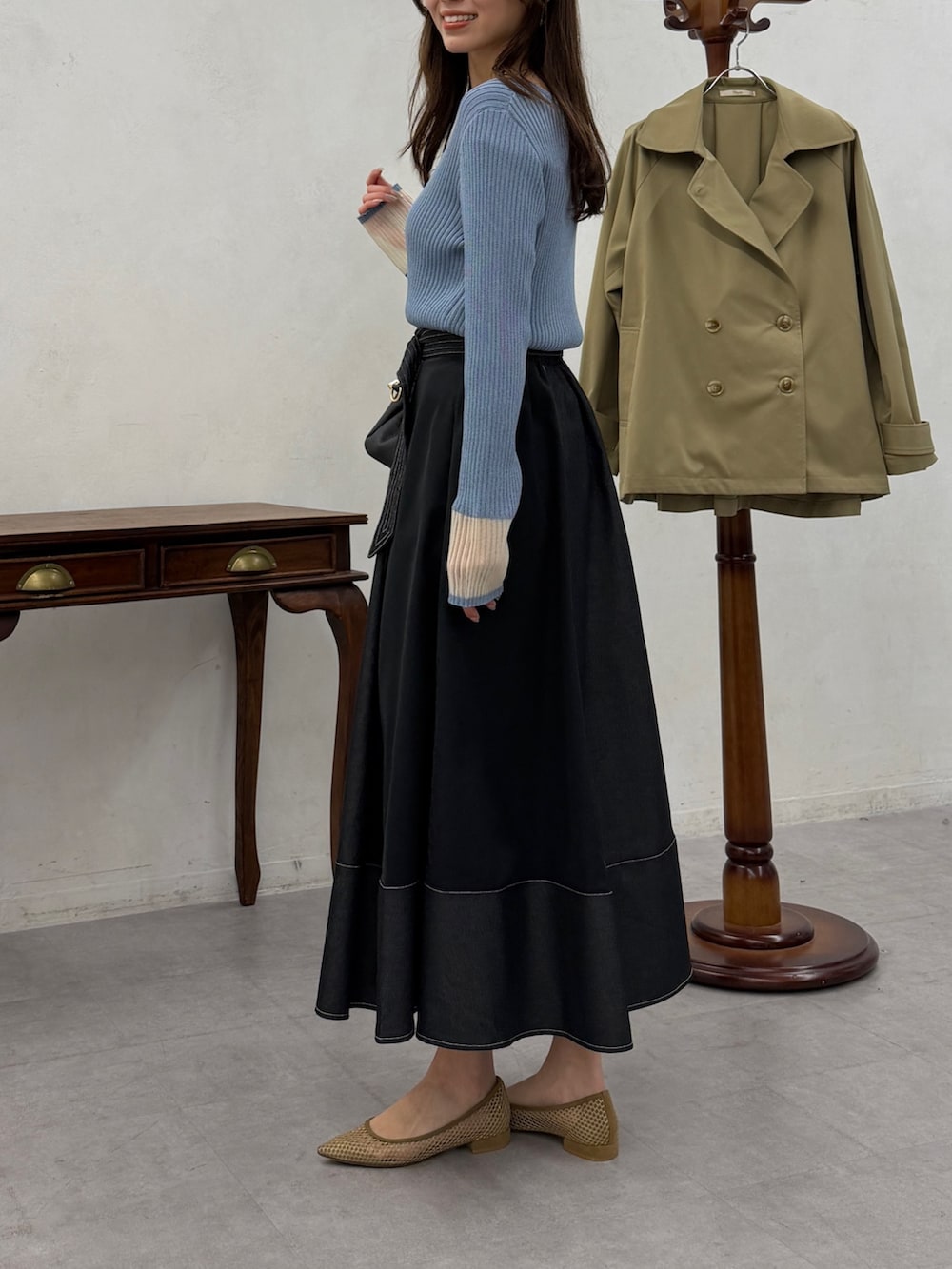 ブルー系のニット/セーター、ブラック系のスカートを着用したレディースの春コーディネートの2枚目の写真