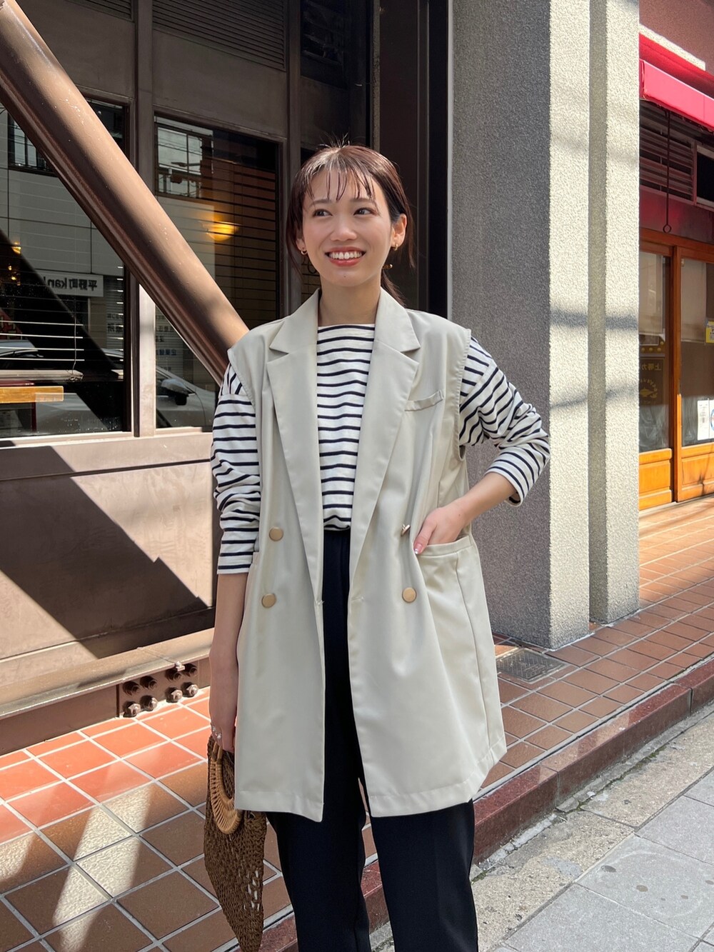 ベージュ系のその他アウター、ホワイト系のトップス、ブラウン系のかごバッグを着用したレディースの春コーディネートの2枚目の写真