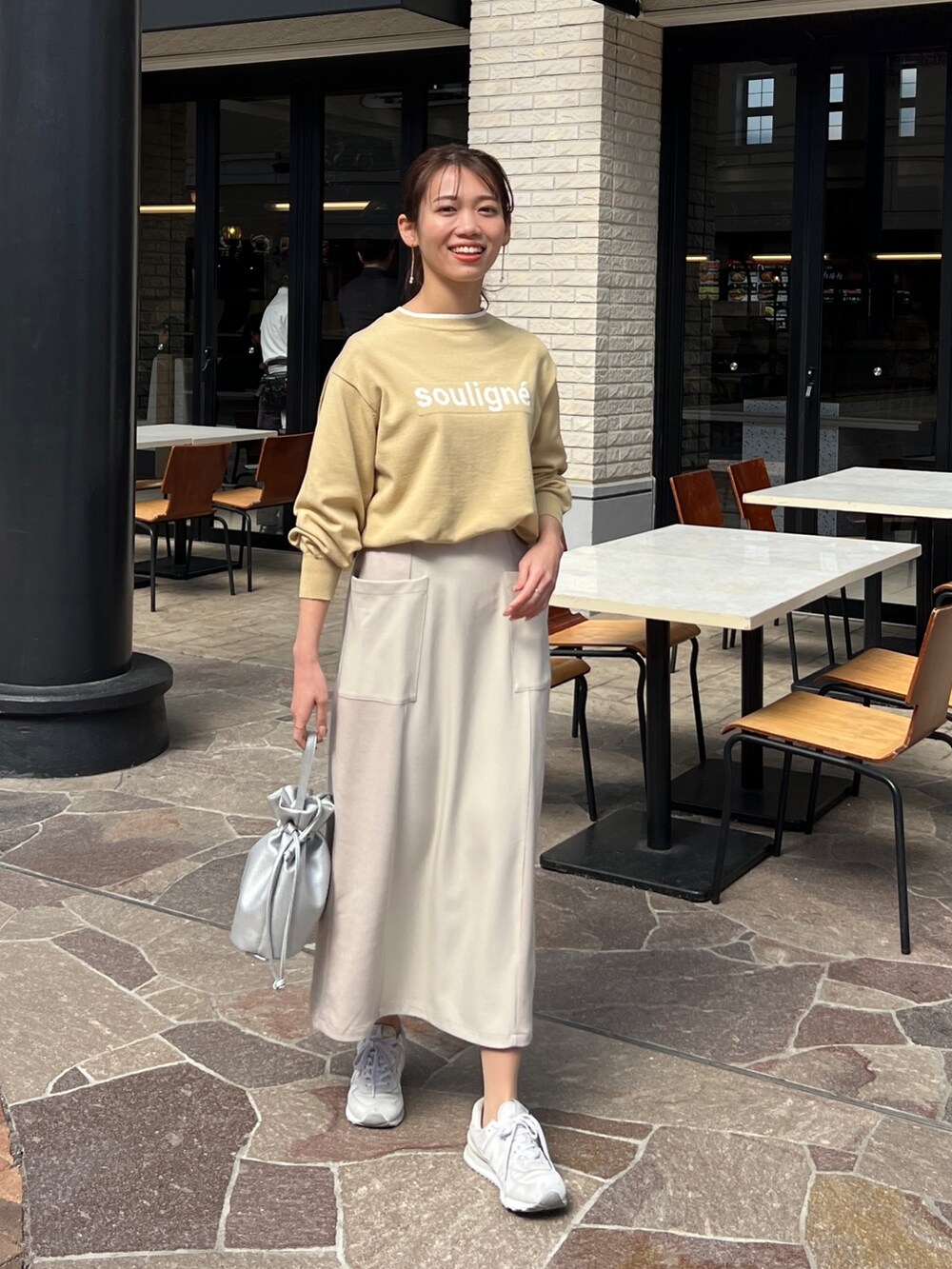 イエロー系のニット/セーター、ブルー系のテーラードジャケット、ホワイト系のスカートを着用したレディースの春コーディネートの2枚目の写真