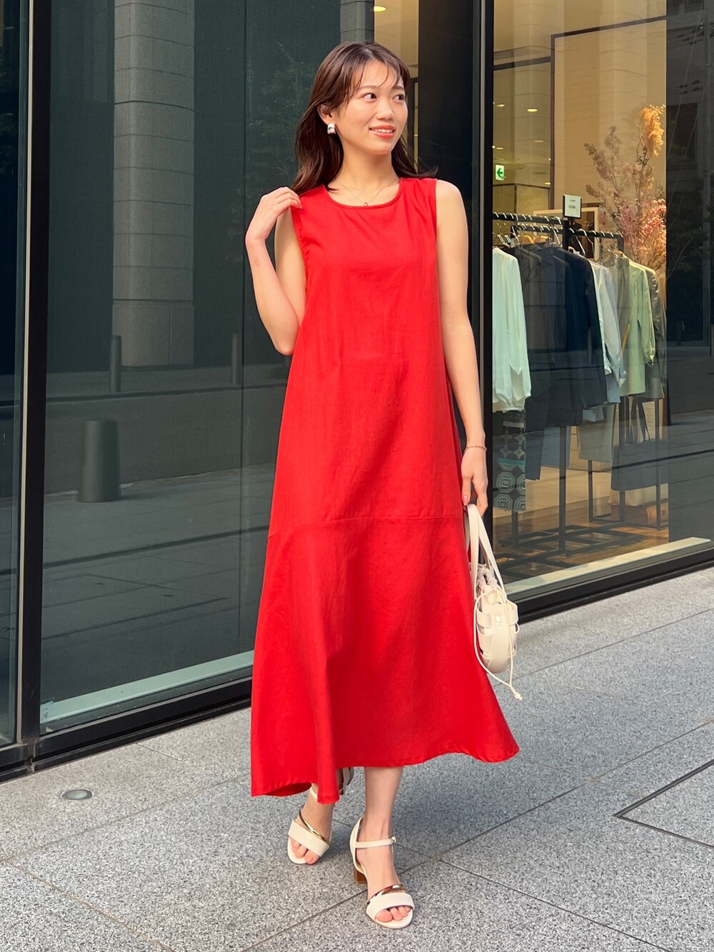 ベージュ系のテーラードジャケット、レッド系のワンピース、ホワイト系のショルダーバッグを着用したレディースの春コーディネートの2枚目の写真