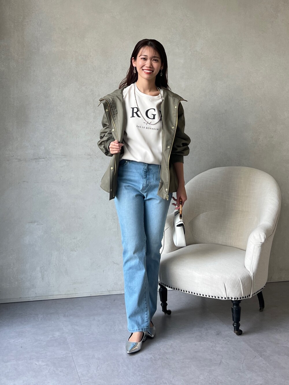 グリーン系のブルゾン、ホワイト系のシャツ/ブラウス、ブルー系のデニムパンツを着用したレディースの冬コーディネートの2枚目の写真