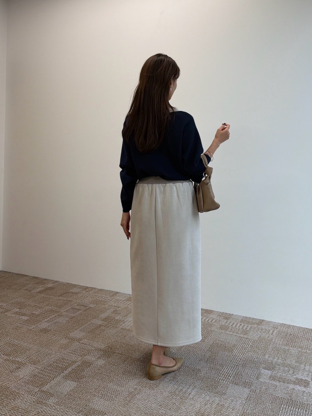 ブルー系のニット/セーター、ブラック系のショルダーバッグ、ベージュ系のスカートを着用したレディースの秋コーディネートの3枚目の写真
