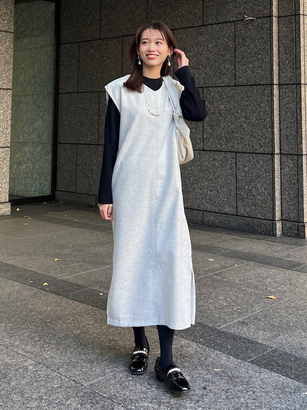 ホワイト系のワンピース、ホワイト系のショルダーバッグ、ブラック系のローファーを着用したレディースの冬コーディネートの2枚目の写真