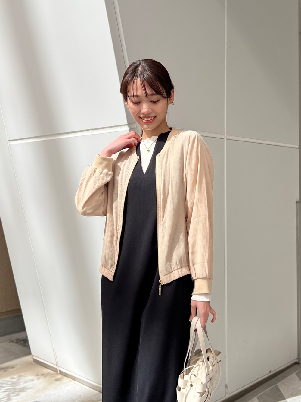 ベージュ系のジャケット/アウター、ブラック系のワンピース、ホワイト系のショルダーバッグを着用したレディースの春コーディネートの3枚目の写真