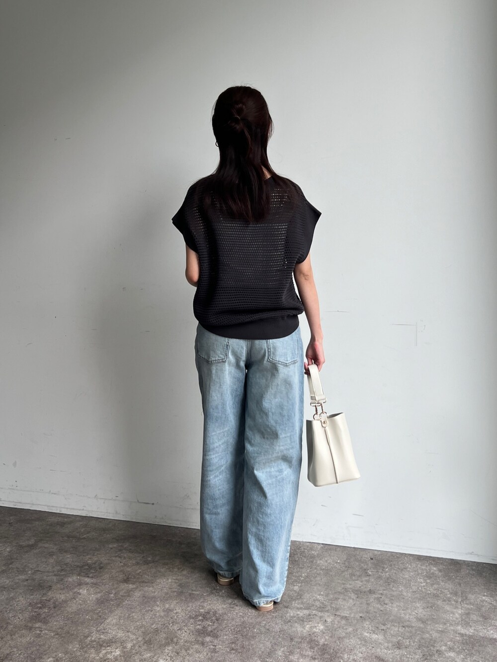 グレー系のニット/セーター、ブルー系のデニムパンツ、ホワイト系のショルダーバッグを着用したレディースの夏コーディネートの2枚目の写真