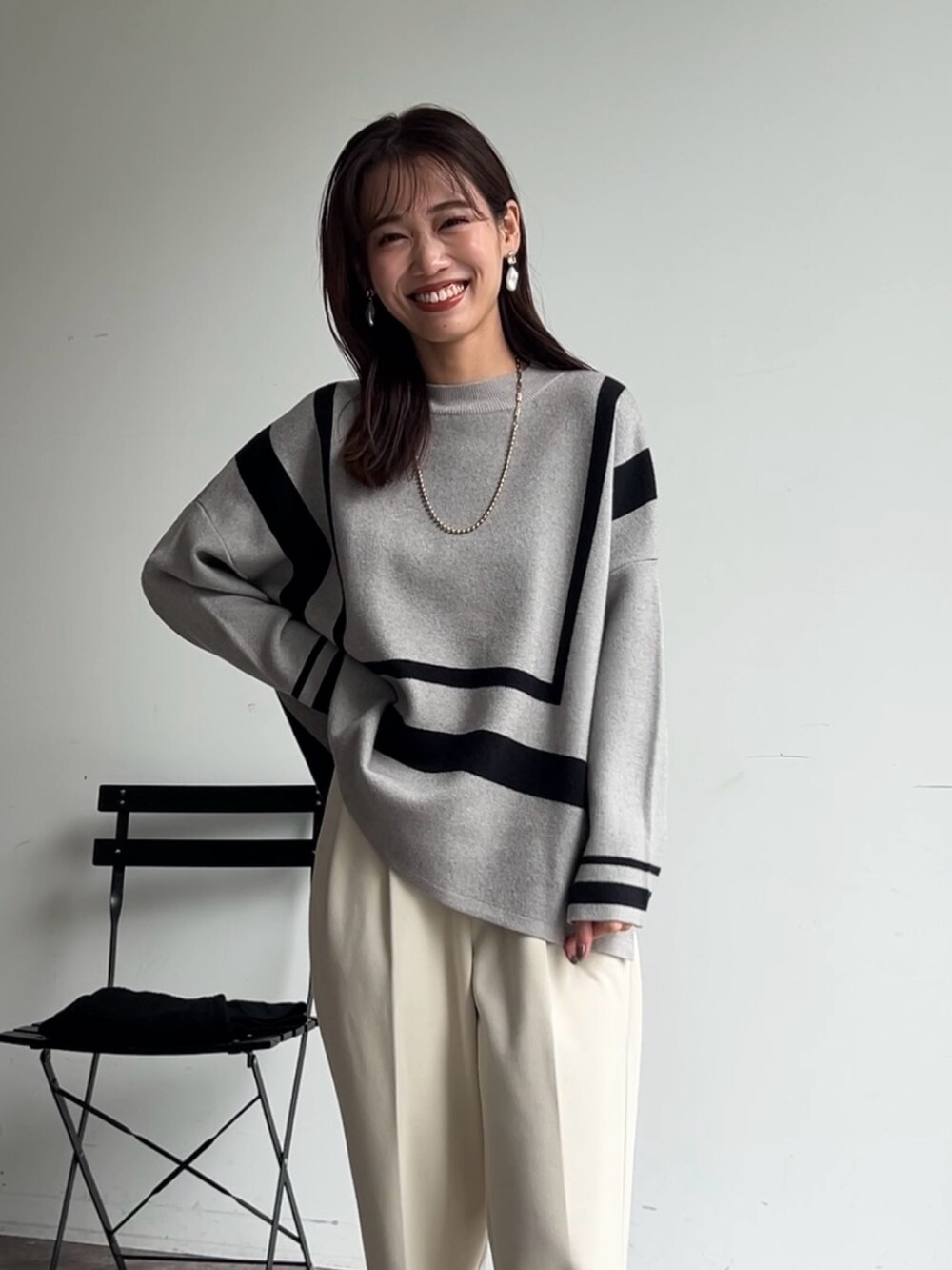 グレー系のニット/セーター、ホワイト系のその他パンツ、ブラック系のブーツを着用したレディースの秋コーディネートの2枚目の写真