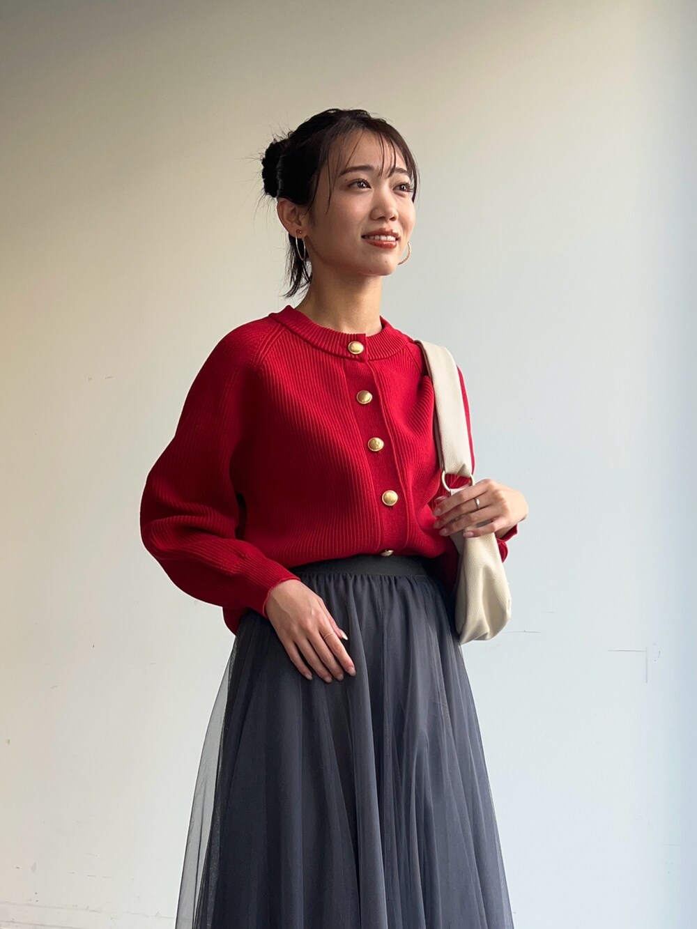 レッド系のニット/セーター、ホワイト系のショルダーバッグ、グレー系のスカートを着用したレディースの冬コーディネートの3枚目の写真