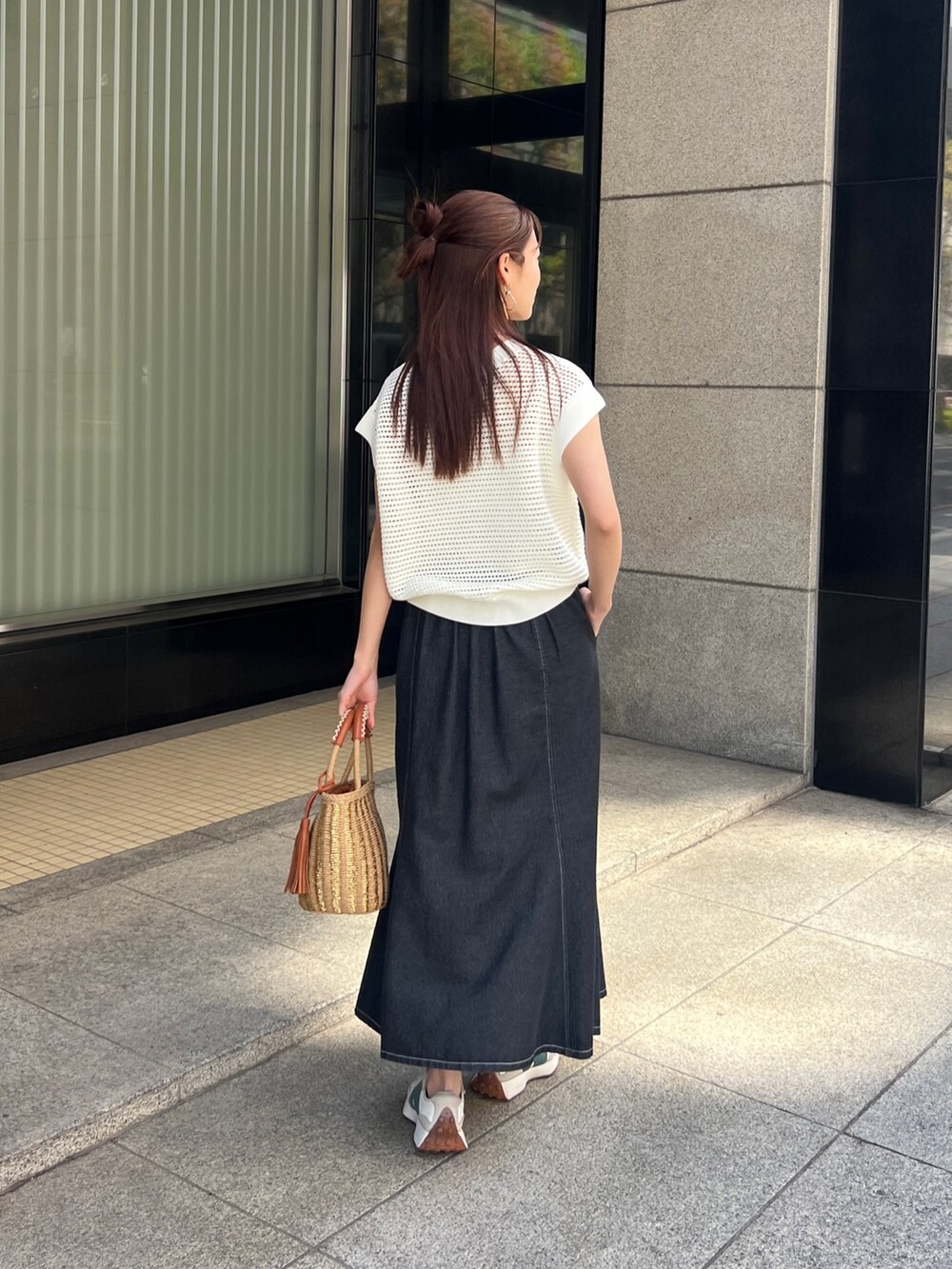 ホワイト系のニット/セーター、ブラック系のスカート、ベージュ系のかごバッグを着用したレディースの春コーディネートの2枚目の写真