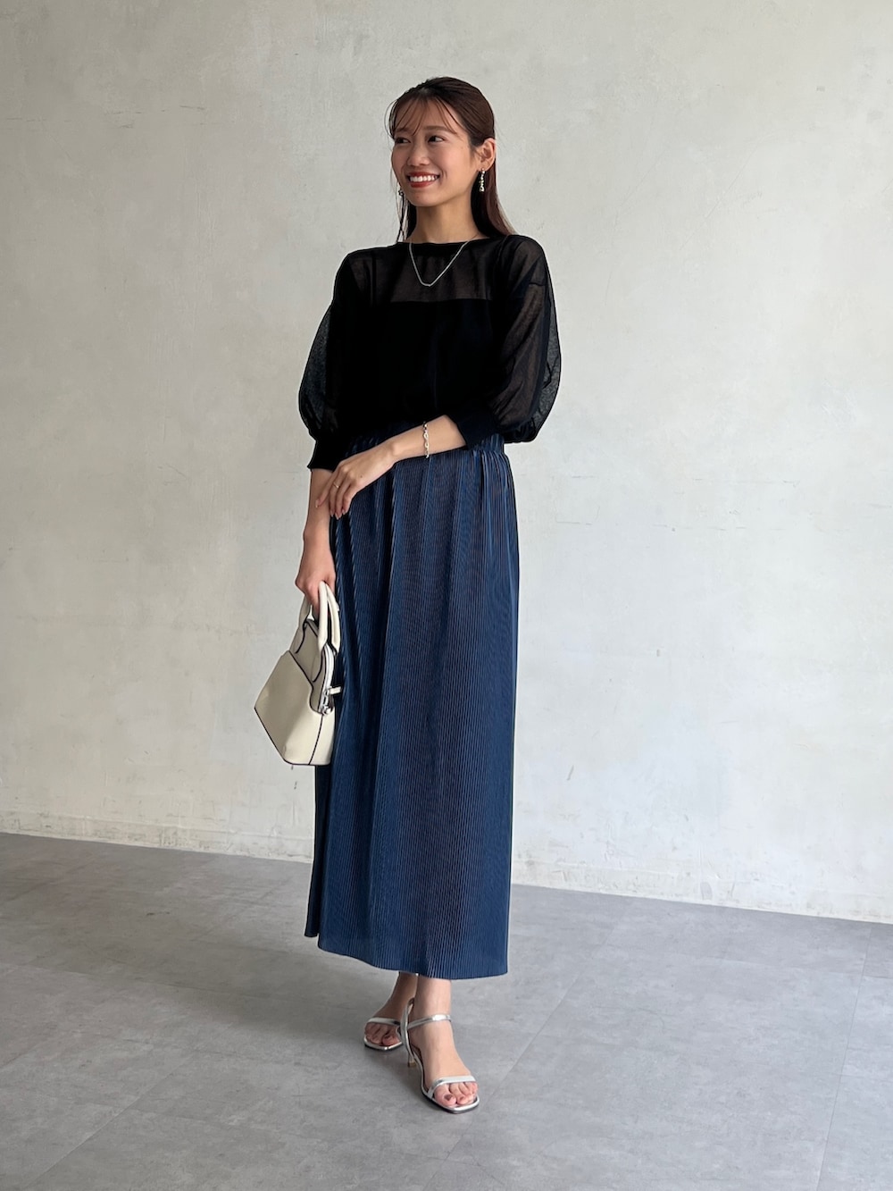 ブラック系のカーディガン/ボレロ、ブルー系のスカート、シルバー系のサンダルを着用したレディースの夏コーディネートの4枚目の写真