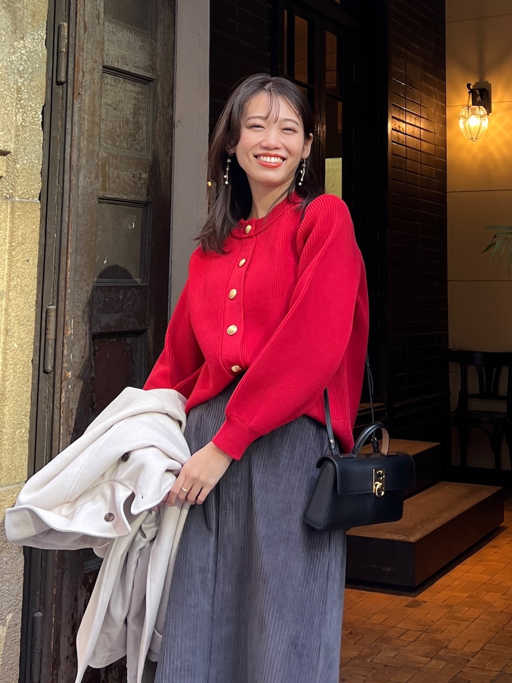 レッド系のニット/セーター、ホワイト系のその他アウター、グレー系のスカートを着用したレディースの冬コーディネートの3枚目の写真