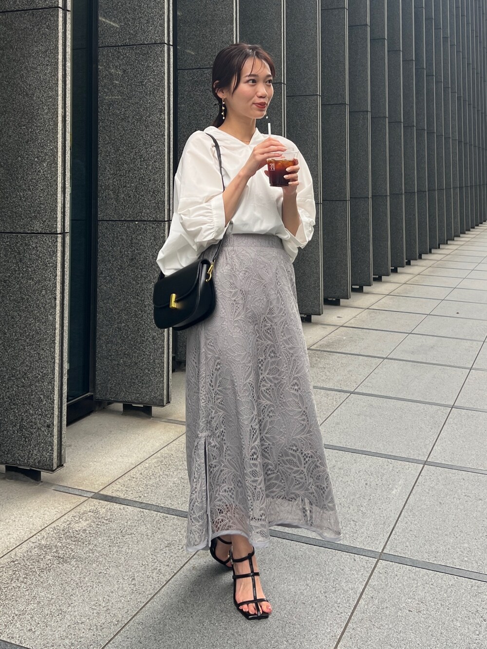 ホワイト系のシャツ/ブラウス、グレー系のスカート、ブラック系のサンダルを着用したレディースの夏コーディネートの2枚目の写真