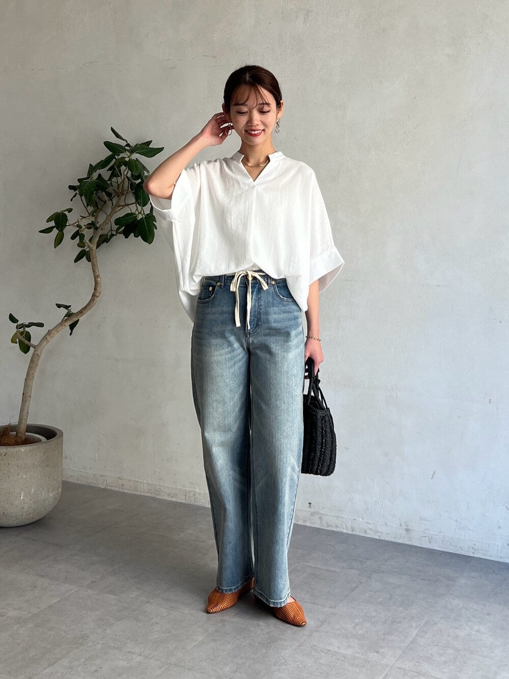 ホワイト系のシャツ/ブラウス、ブルー系のデニムパンツ、ブラック系のかごバッグを着用したレディースの春コーディネートの4枚目の写真