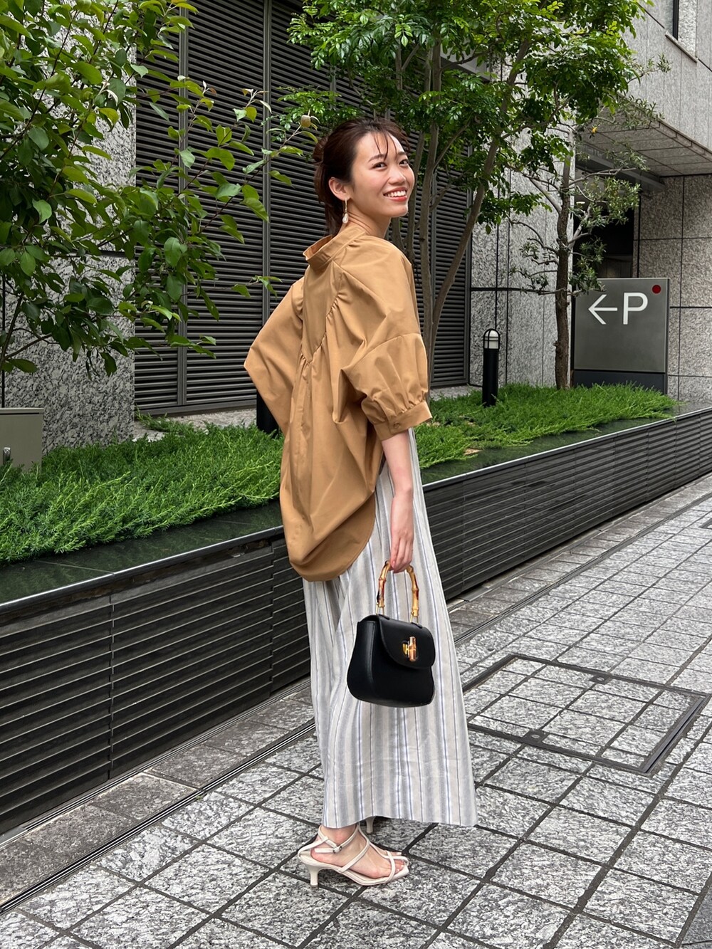 イエロー系のシャツ/ブラウス、ベージュ系のその他パンツ、ホワイト系のサンダルを着用したレディースの春コーディネートの2枚目の写真