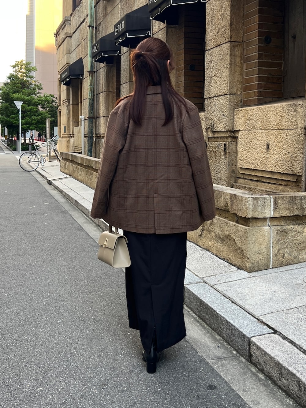 ブラウン系のテーラードジャケット、ブラック系のワンピース、ブラック系のブーツを着用したレディースの秋コーディネートの3枚目の写真