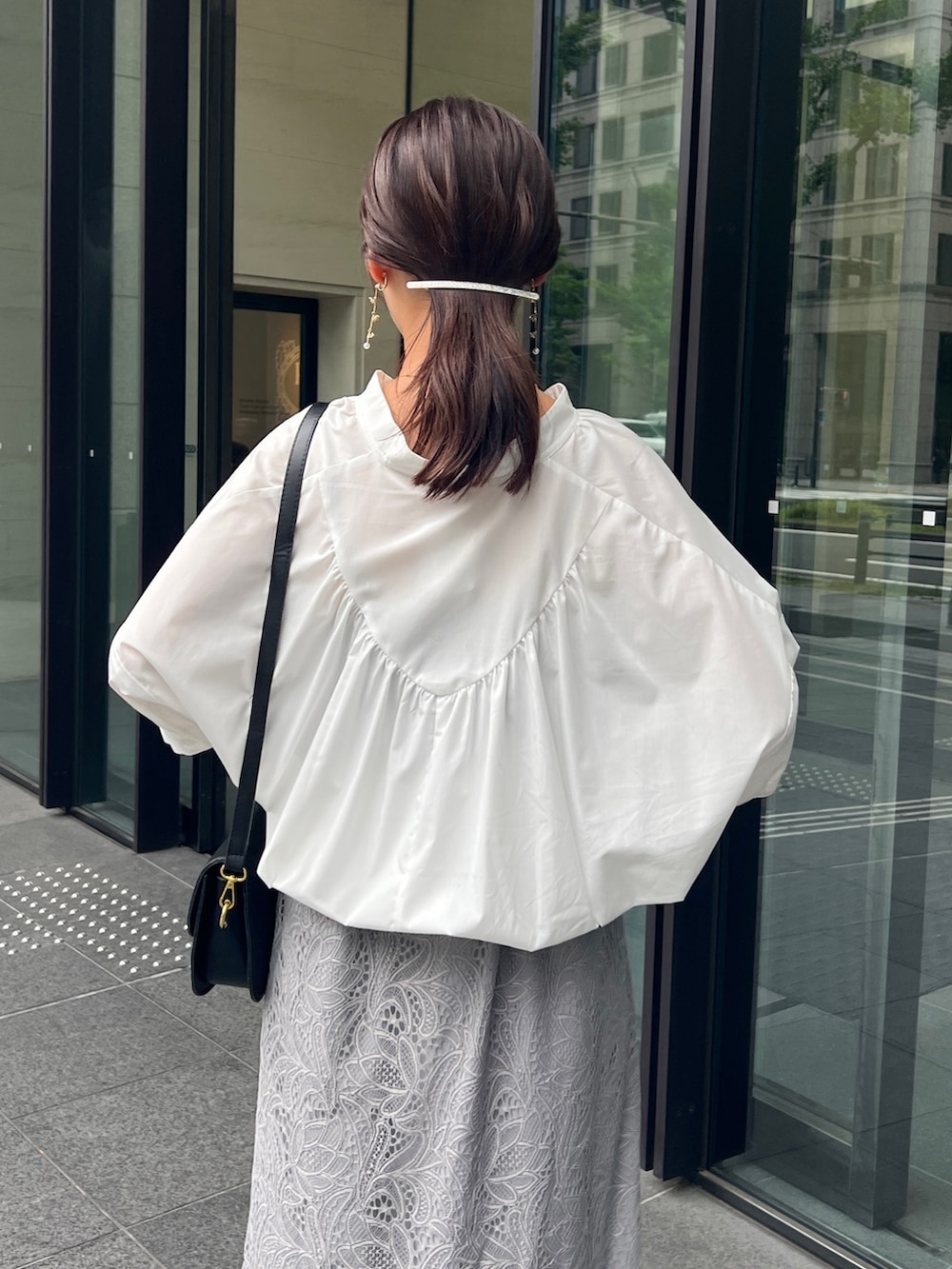ホワイト系のシャツ/ブラウス、グレー系のスカート、ブラック系のサンダルを着用したレディースの夏コーディネートの3枚目の写真