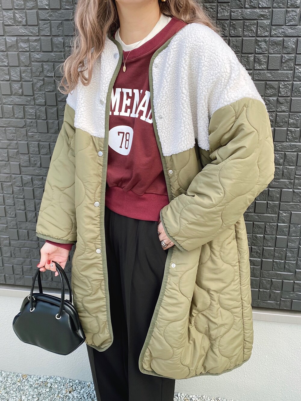 グリーン系のノーカラーコート、ブラック系のバッグ、レッド系のスウェットを着用したレディースの冬コーディネートの3枚目の写真