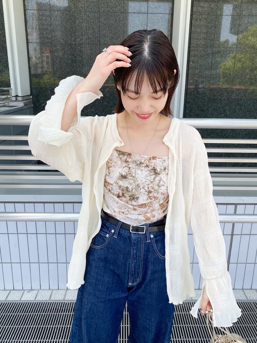 ブルー系のデニムパンツ、グリーン系のキャミソール、ホワイト系のシャツ/ブラウスを着用したレディースの春コーディネートの3枚目の写真