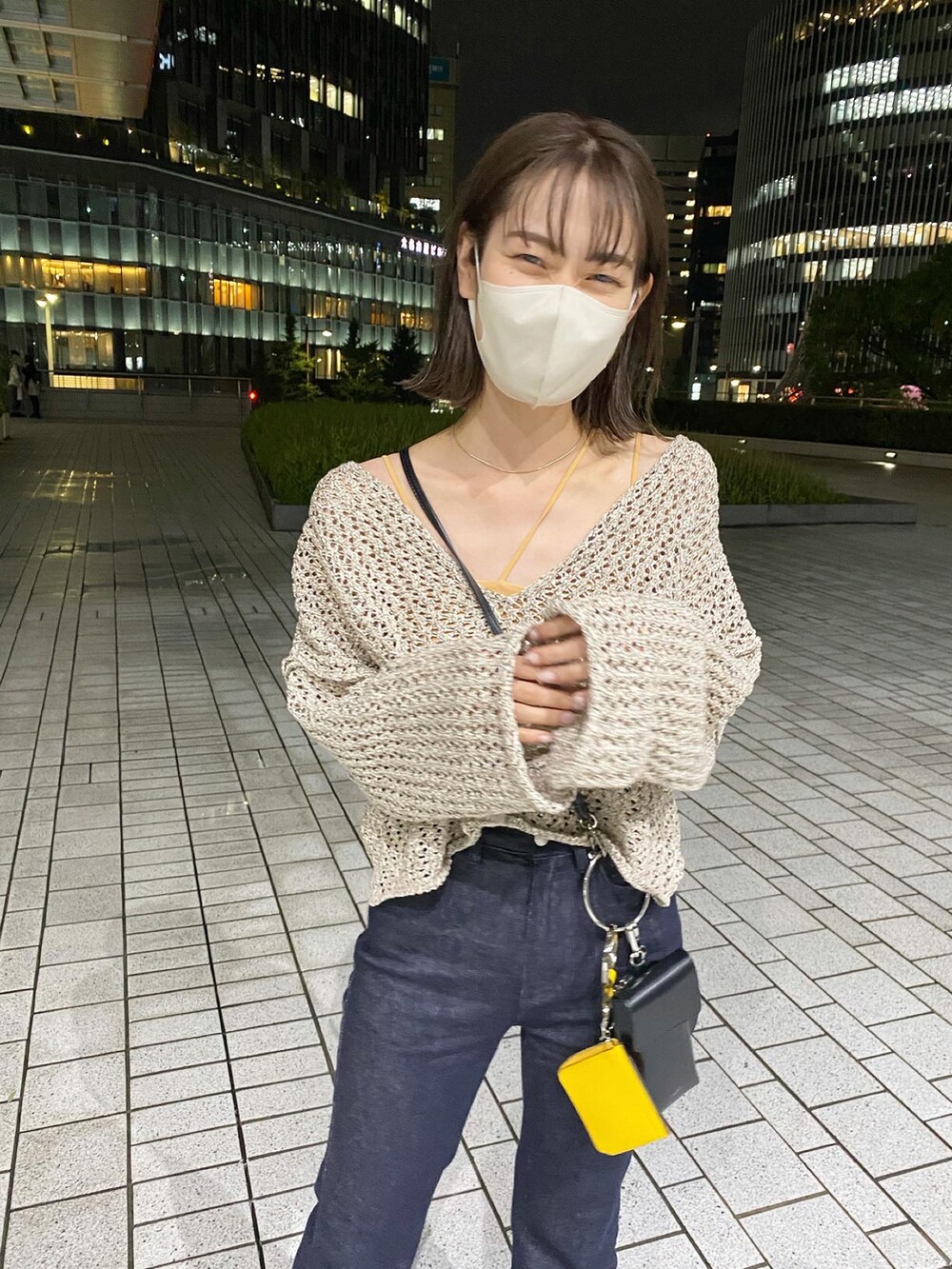 ベージュ系のニット/セーター、ブラック系のトートバッグ、ブルー系のデニムパンツを着用したレディースの夏コーディネートの2枚目の写真