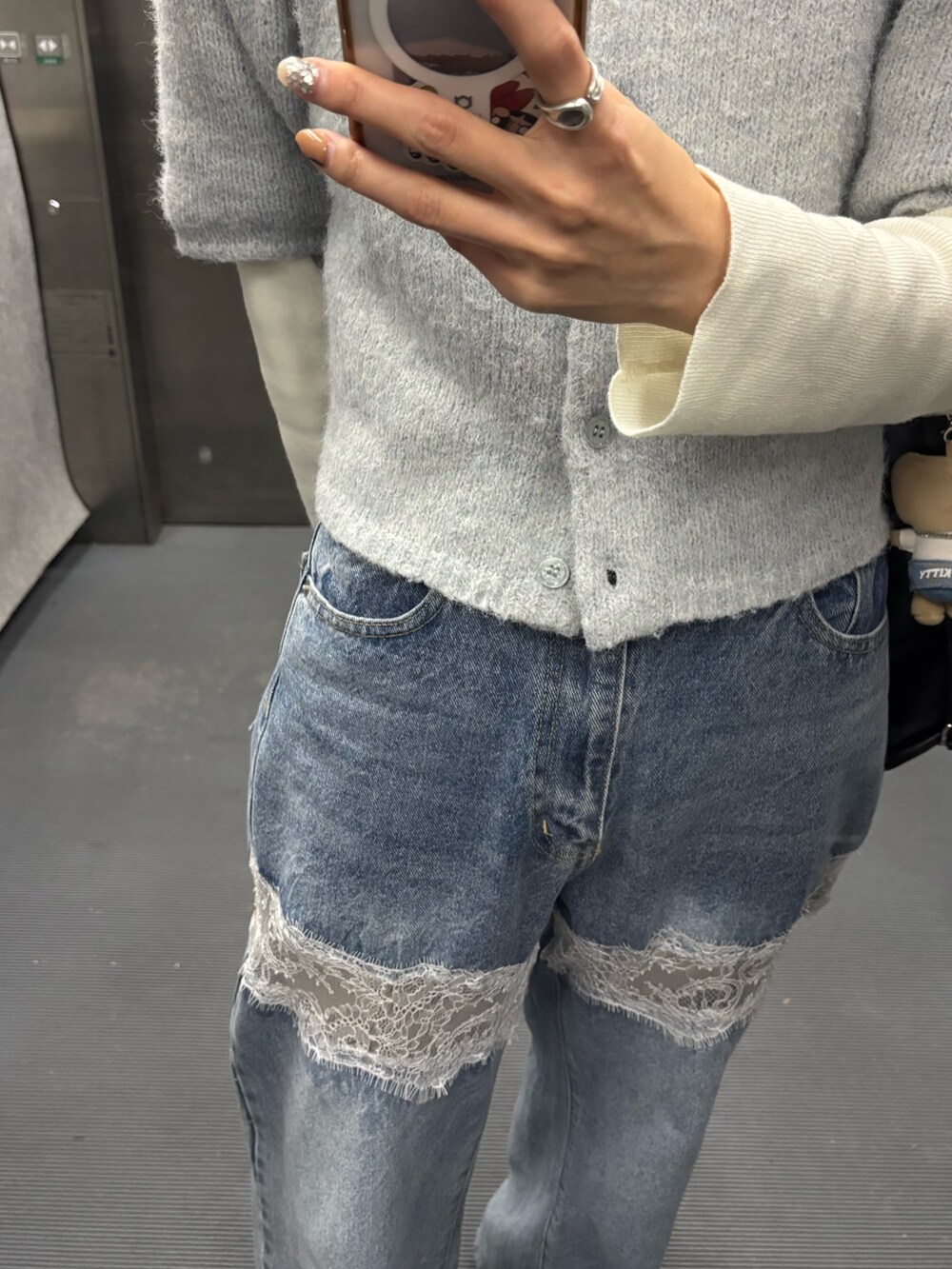 ブルー系のカーディガン/ボレロ、ホワイト系のニット/セーター、ブルー系のデニムパンツを着用したレディースの冬コーディネートの3枚目の写真