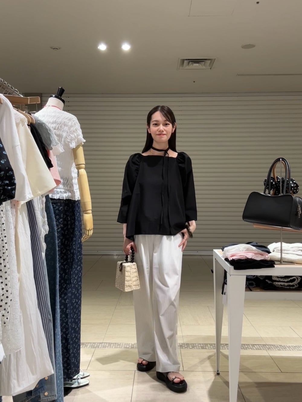 ブラック系のシャツ/ブラウス、ホワイト系のスラックス、ブラック系のサンダルを着用したレディースの春コーディネートの2枚目の写真