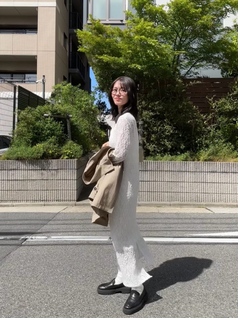 ホワイト系のワンピース、ベージュ系のトレンチコート、レッド系のネックレスを着用したレディースの春コーディネートの2枚目の写真