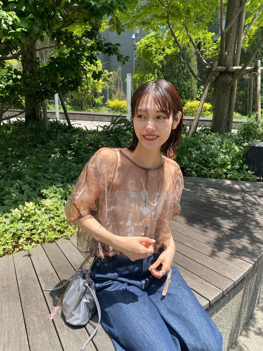 ブラウン系のシャツ/ブラウス、ブルー系のデニムパンツを着用したレディースの夏コーディネートの2枚目の写真