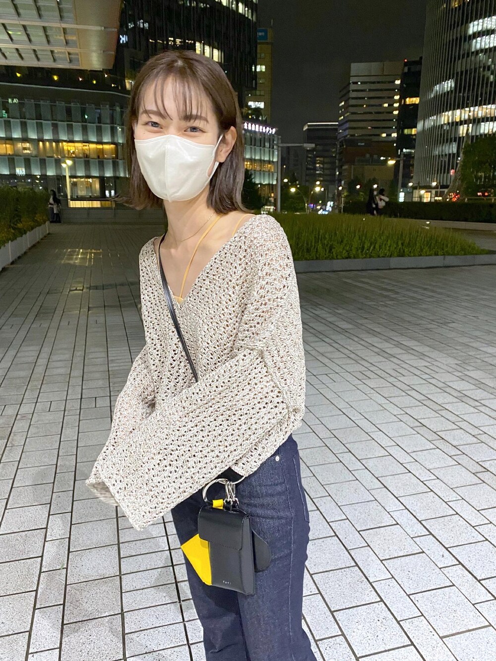 ベージュ系のニット/セーター、ブラック系のトートバッグ、ブルー系のデニムパンツを着用したレディースの夏コーディネートの3枚目の写真