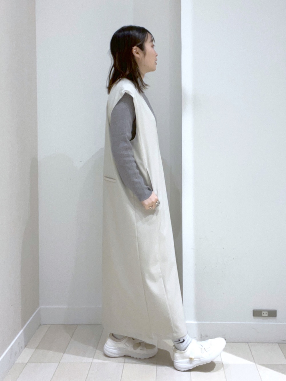 ブラック系のショルダーバッグ、ホワイト系のジャンパースカート、ホワイト系のスニーカーを着用したレディースの冬コーディネートの3枚目の写真