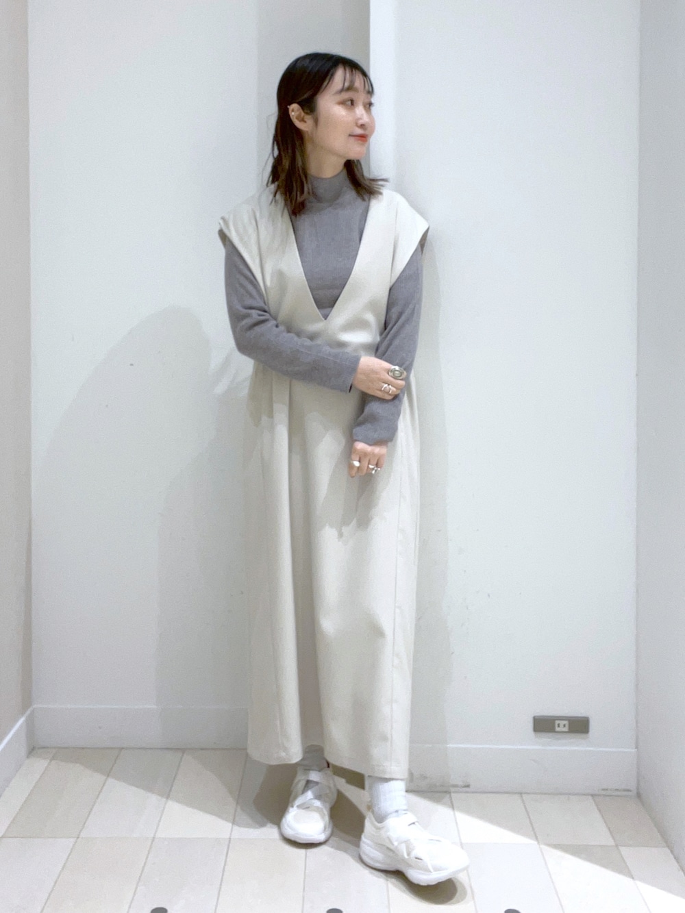 ブラック系のショルダーバッグ、ホワイト系のジャンパースカート、ホワイト系のスニーカーを着用したレディースの冬コーディネートの2枚目の写真