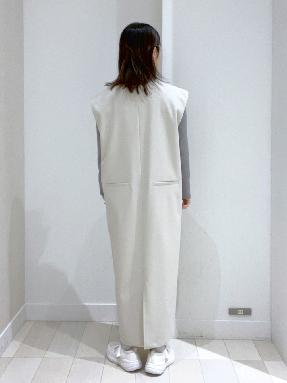 ブラック系のショルダーバッグ、ホワイト系のジャンパースカート、ホワイト系のスニーカーを着用したレディースの冬コーディネートの4枚目の写真