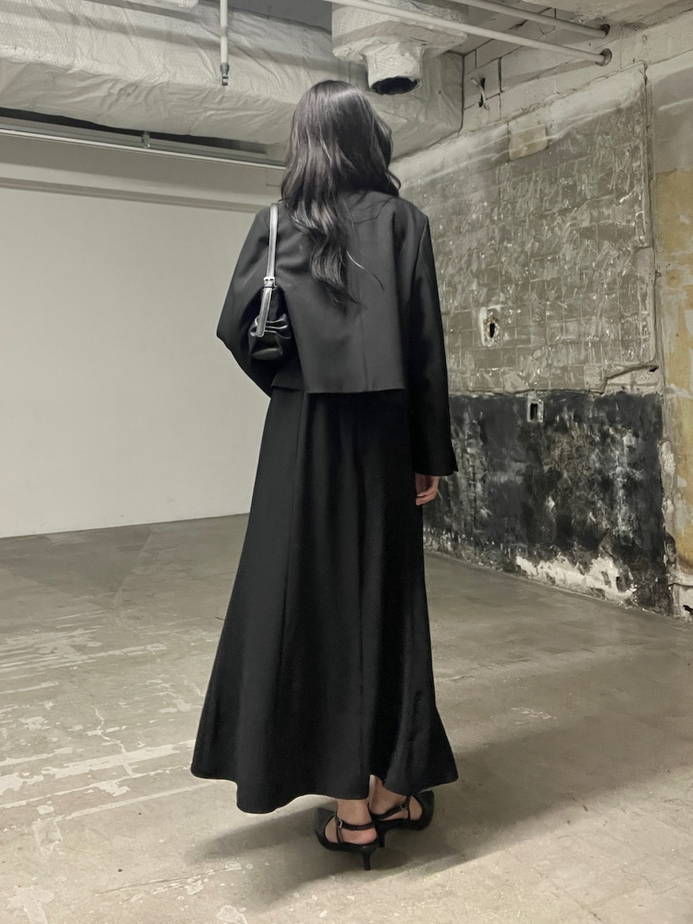 ブラック系のワンピース、ブラック系のパンプス、ブラック系のハンドバッグを着用したレディースの秋コーディネートの4枚目の写真