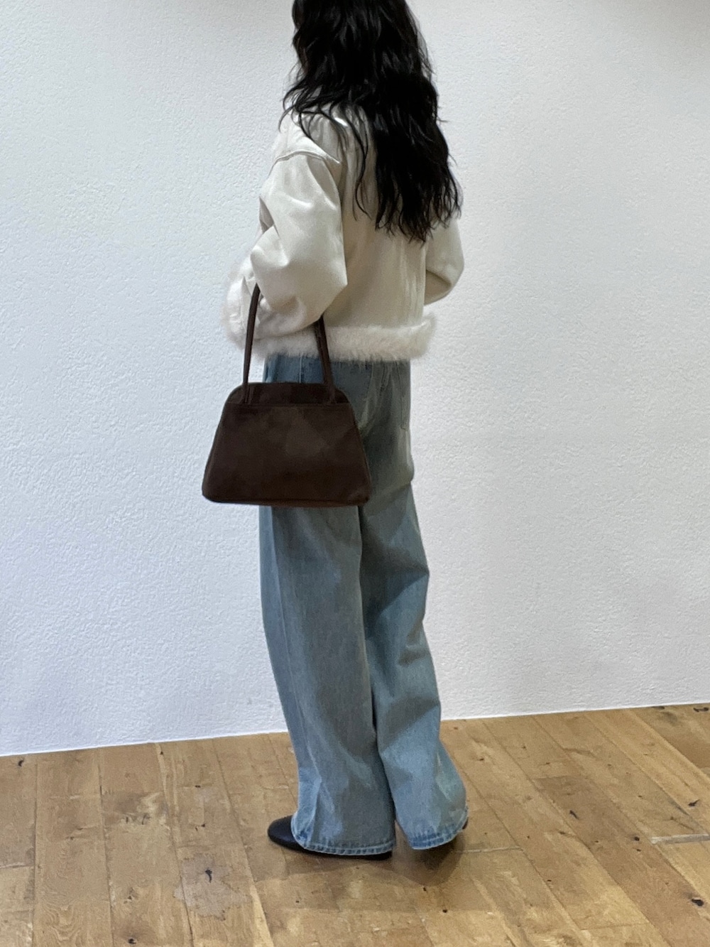ブルー系のデニムパンツ、ホワイト系のライダースジャケット、ブラウン系のボストンバッグを着用したレディースの秋コーディネートの3枚目の写真