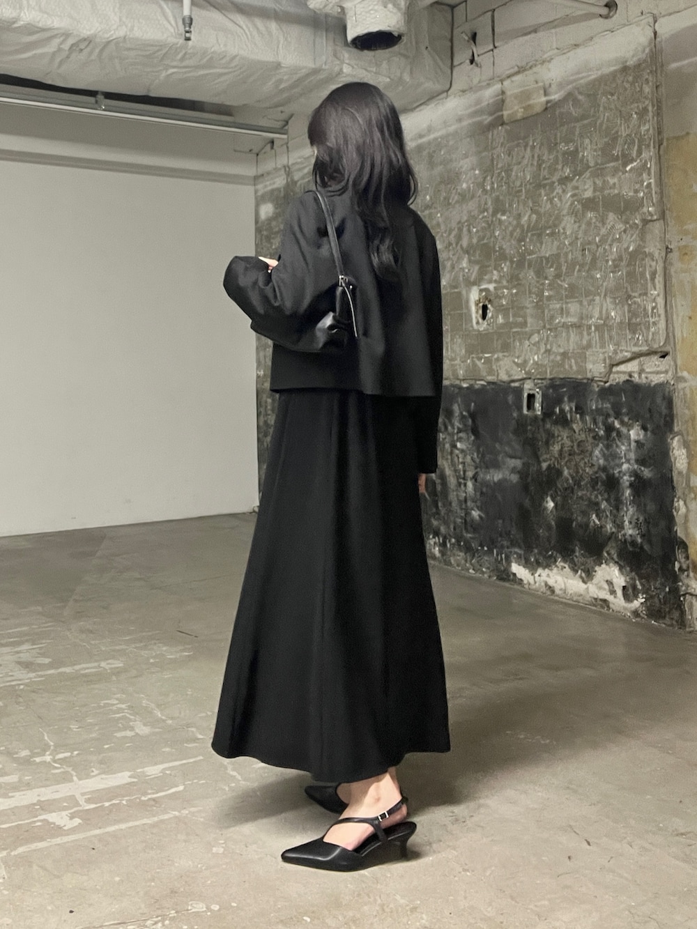 ブラック系のワンピース、ブラック系のパンプス、ブラック系のハンドバッグを着用したレディースの秋コーディネートの3枚目の写真