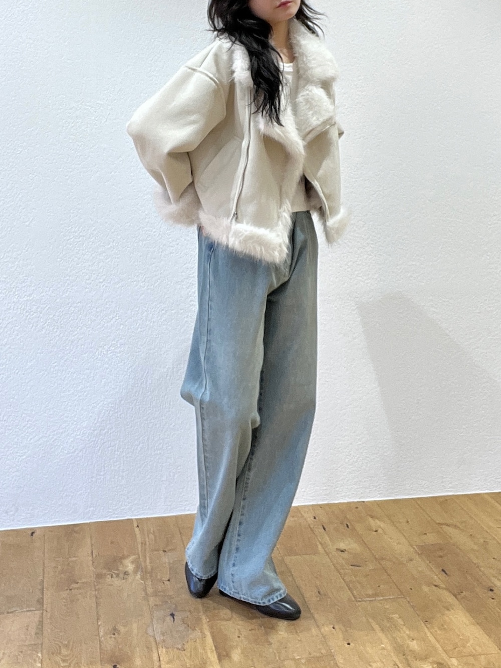 ブルー系のデニムパンツ、ホワイト系のライダースジャケット、ブラウン系のボストンバッグを着用したレディースの秋コーディネートの4枚目の写真