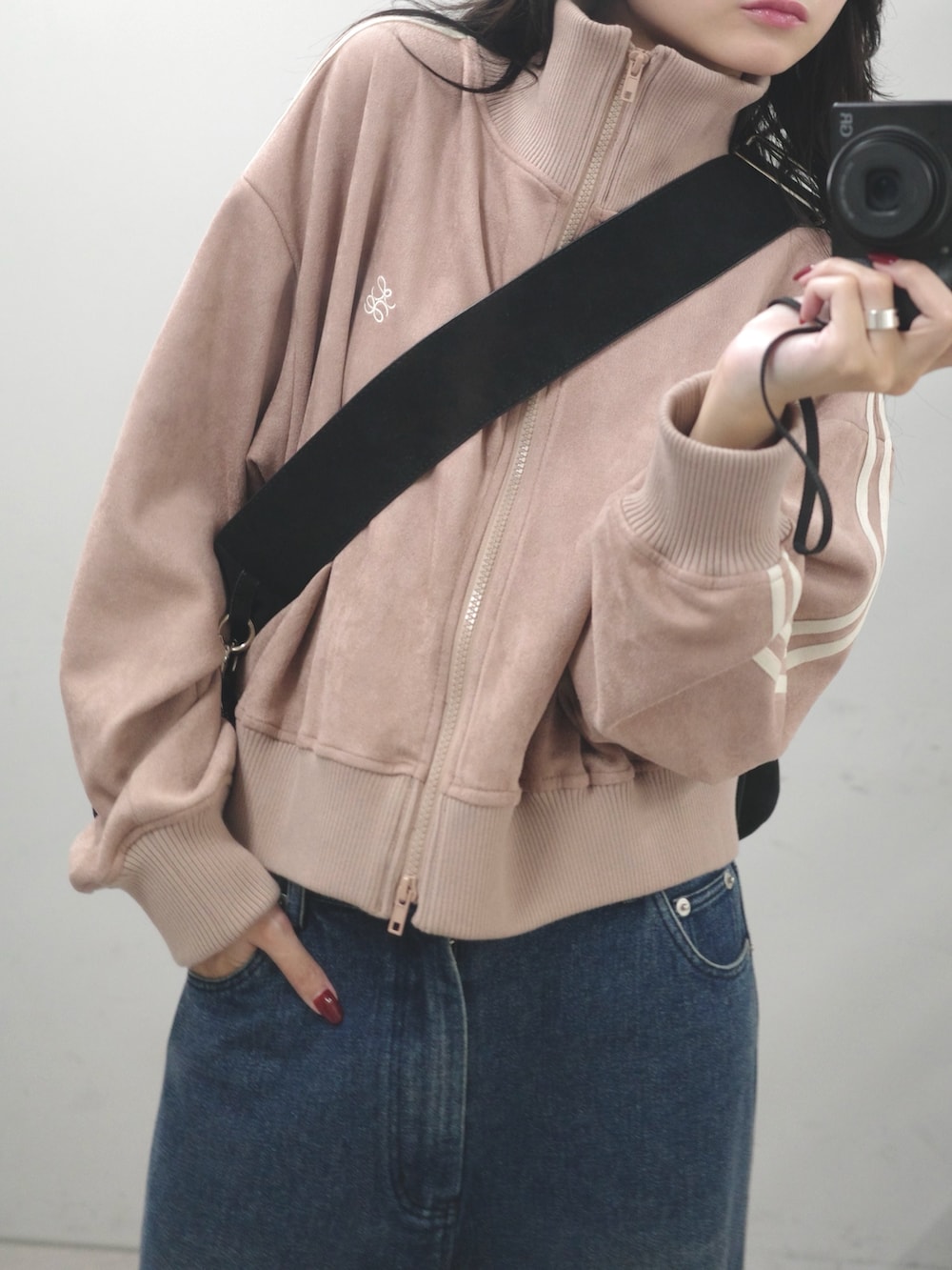 ブルー系のデニムパンツ、ピンク系のブルゾン、ブラック系のショルダーバッグを着用したレディースの秋コーディネートの2枚目の写真