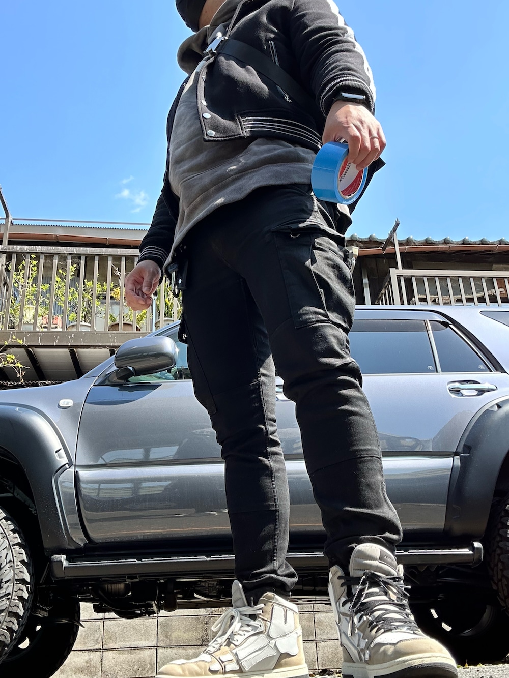 ベージュ系のスニーカー、ブラック系のカーゴパンツ、ブルー系のパーカーを着用したメンズの春コーディネートの2枚目の写真