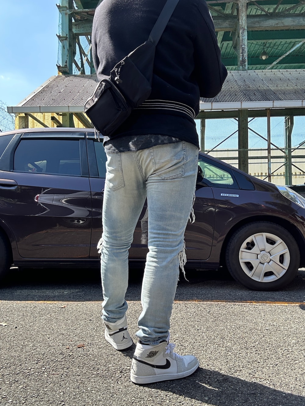 ホワイト系のスニーカー、ブルー系のデニムパンツ、ブラック系のブルゾンを着用したメンズの春コーディネートの2枚目の写真