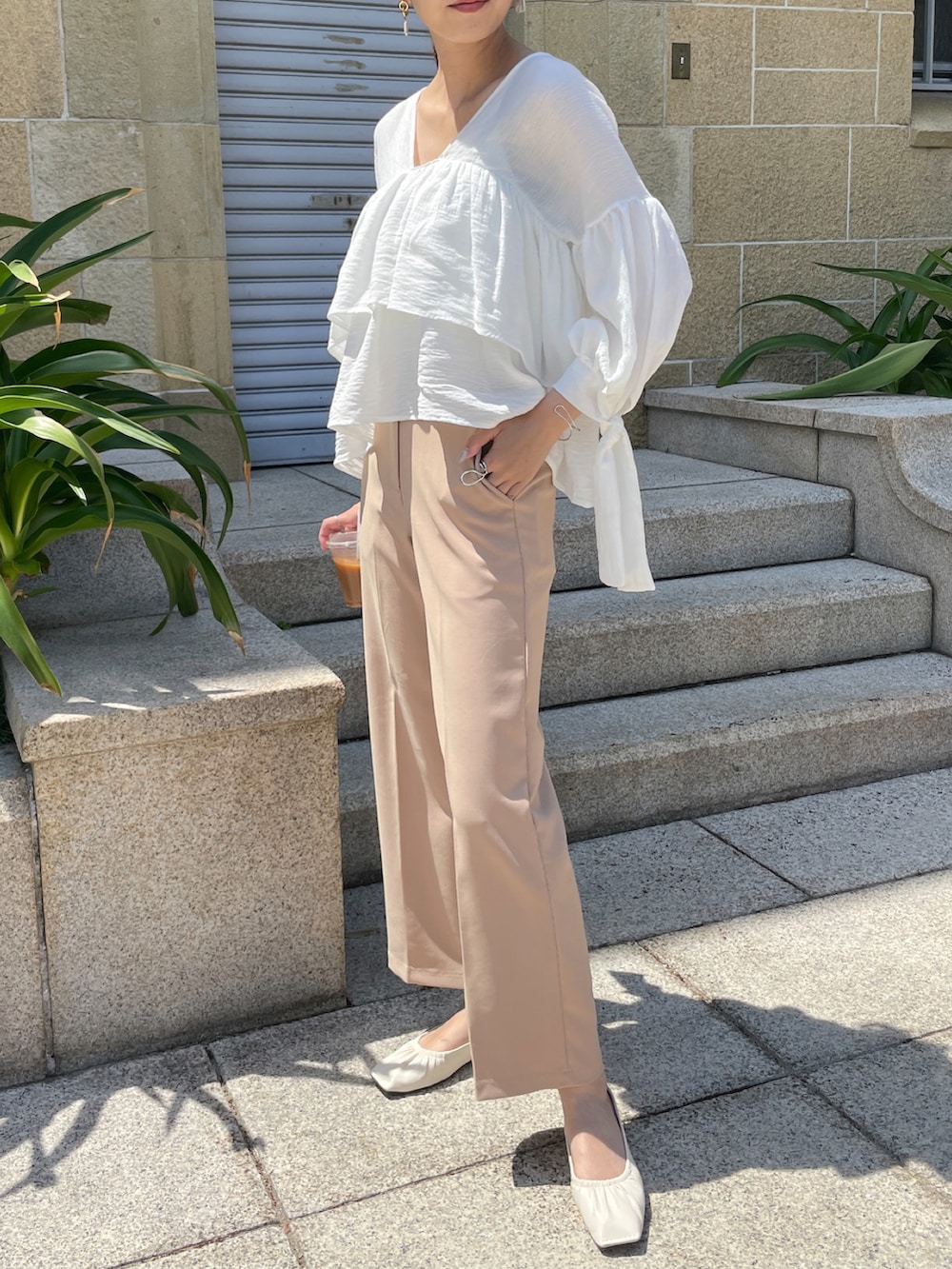 ベージュ系のスラックス、ホワイト系のパンプス、ホワイト系のシャツ/ブラウスを着用したレディースの春コーディネートの2枚目の写真