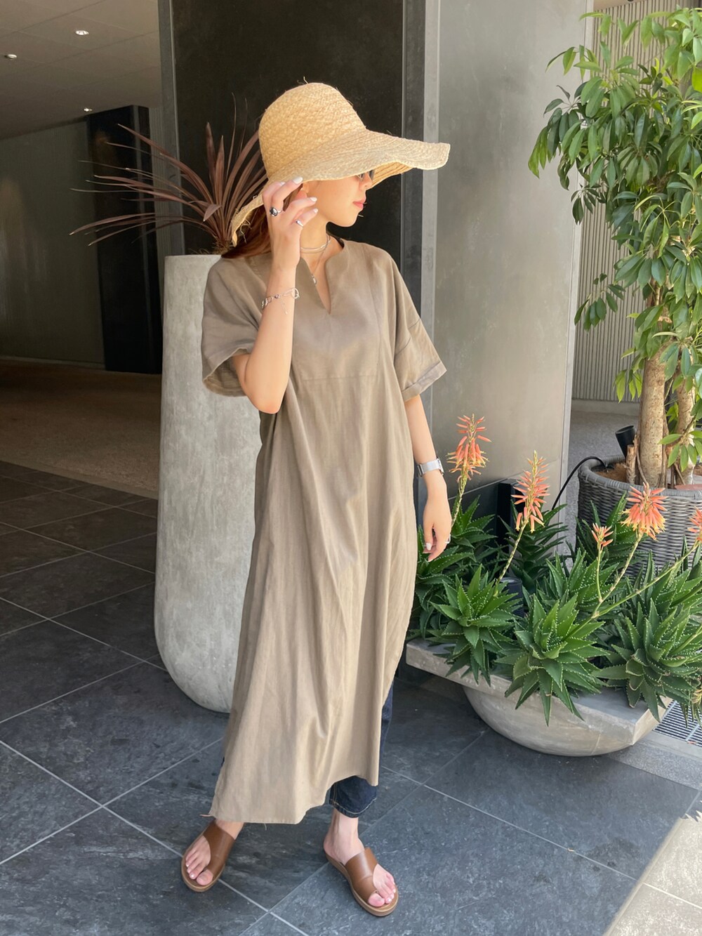 ブラウン系のワンピース、イエロー系のサンダル、ブルー系のデニムパンツを着用したレディースの夏コーディネートの2枚目の写真