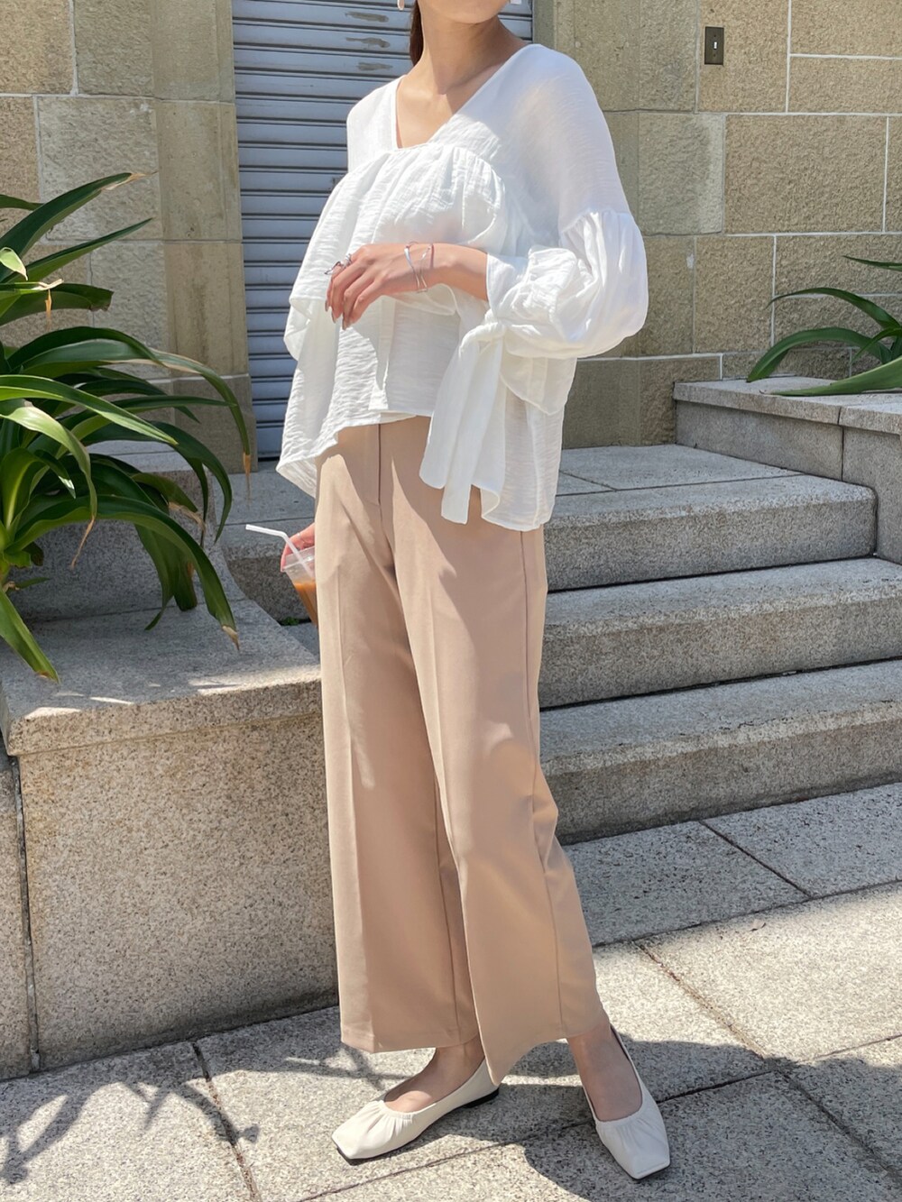 ベージュ系のスラックス、ホワイト系のパンプス、ホワイト系のシャツ/ブラウスを着用したレディースの春コーディネートの3枚目の写真